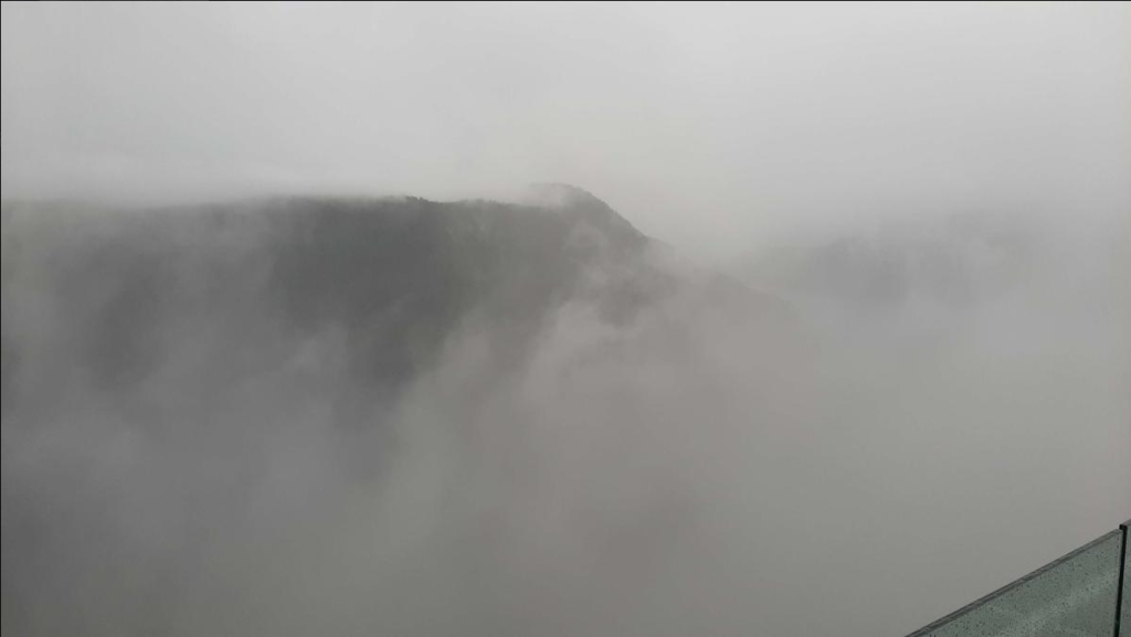 Photo taken where it is foggy and barely can see the mountains with trees on the other side of the valley. Supposedly, it is a big valley that looks great from here, but it was obscured by fog.